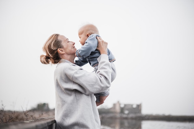 Donna tenera che accarezza il suo bambino bambino all'aperto in viaggio d'autunno a secovlje salinas