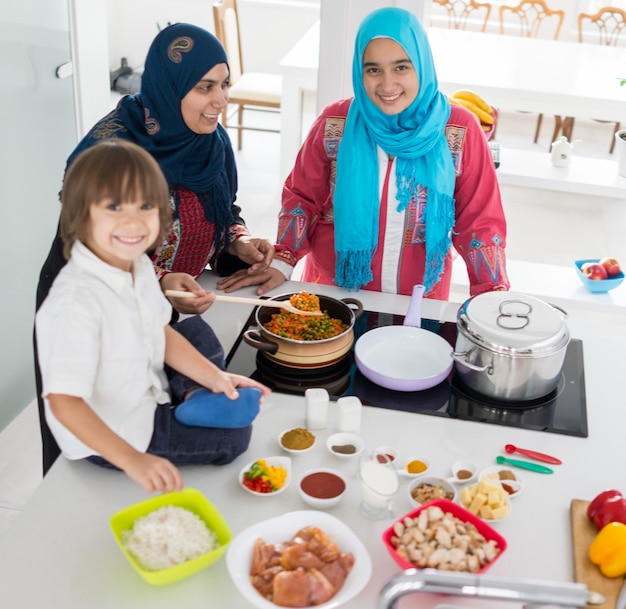 Donna tradizionale musulmana con il piccolo figlio in cucina bianca moderna