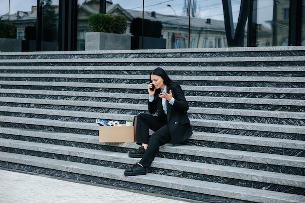 Donna travagliata seduta sulle scale che discute di lavoro licenziato su Smartphone