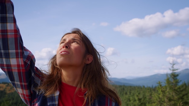 Donna triste che tiene in mano lo smartphone in cima alla montagna Ragazza stressata che cattura la rete mobile all'aperto Escursionista femminile che cerca di chiamare il cellulare in montagna durante le vacanze