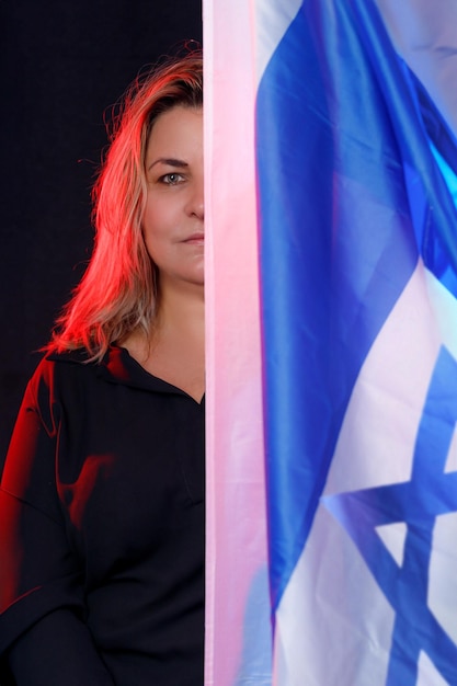 Donna triste con una grande bandiera di Israele che posa tristemente sullo sfondo scuro in uno studio