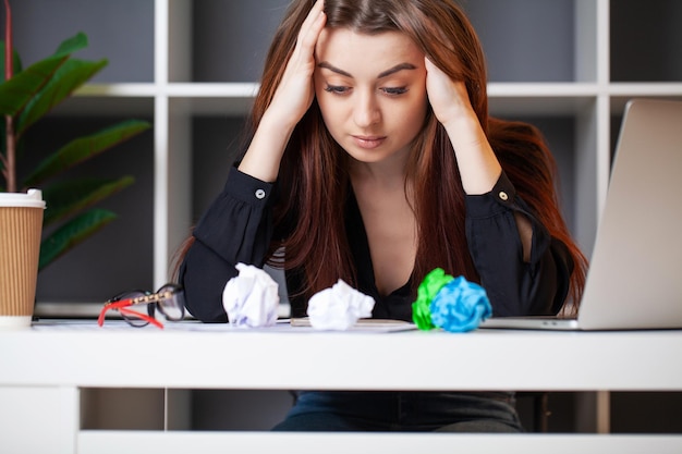 Donna triste di affari in ufficio che lavora al computer portatile