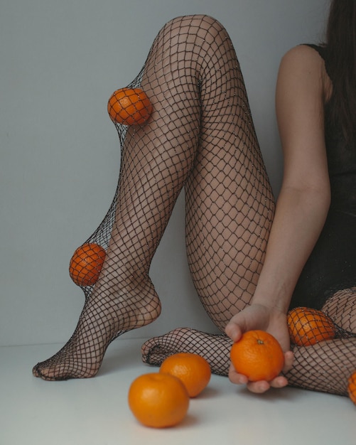 Donna triste in lingerie nera, collant a rete di formiche con mandarini.