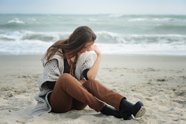 Donna triste sola seduta su una spiaggia del mare