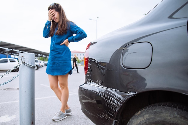 Donna triste vicino all'auto graffiata. ammaccatura dell'auto. copia spazio.assicurazione auto