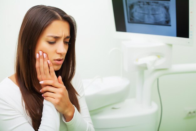 Donna turbata dal dentista con dolore ai denti pulsante costante.