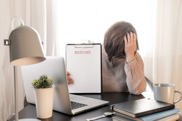 Donna turbata ha chiuso la tua faccia delle mani vicino al suo posto di lavoro con il laptop e riprendi l'applicazione.