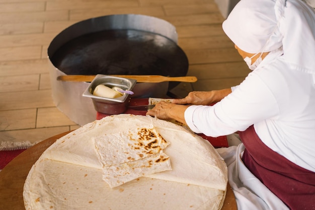 Donna turca che fa tortillas su un tavolo rustico in legno