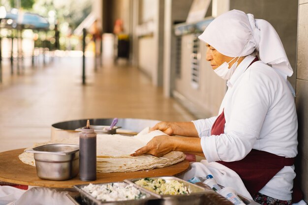 Donna turca che fa tortillas su un tavolo rustico in legno