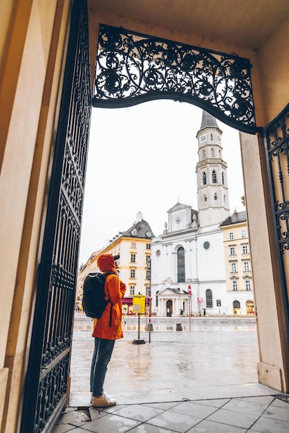 donna turista in impermeabile giallo con zaino che guarda la chiesa di San Michele