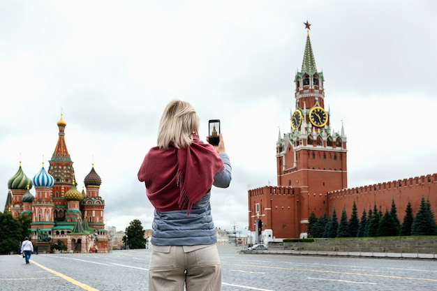 Donna turistica che cattura foto sul suo smartphone sulla Piazza Rossa a Mosca, Russia.