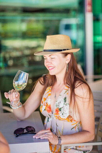 Donna turistica che degusta e beve vino bianco in un caffè di strada