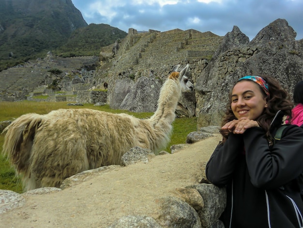 Donna turistica che posa felicemente accanto a un lama a Cusco