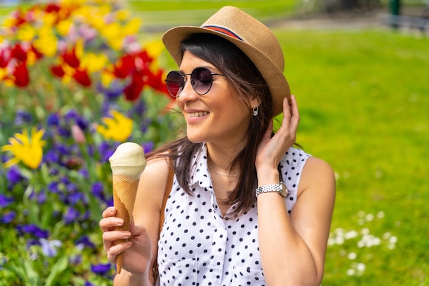 Donna turistica che si diverte a visitare la città mangiando un gelato al pistacchio godendosi le vacanze estive e avendo un concetto di viaggiatore femminile da solo con la macchina fotografica