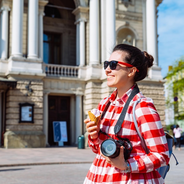 Donna turistica con macchina fotografica e gelato nel mezzo della città europea