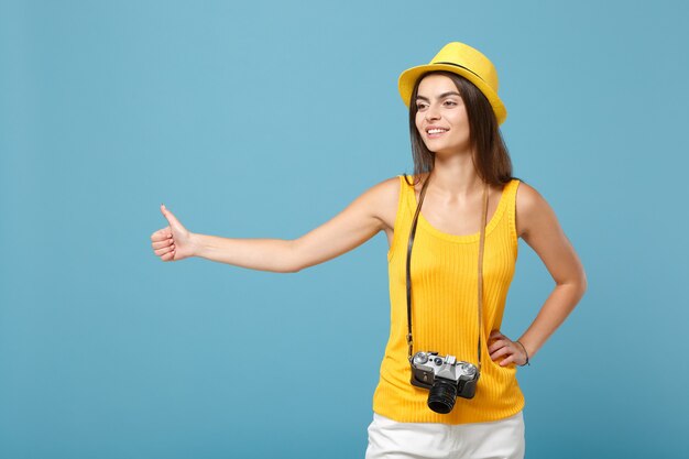 donna turistica in abiti casual estivi gialli e cappello con macchina fotografica su blu