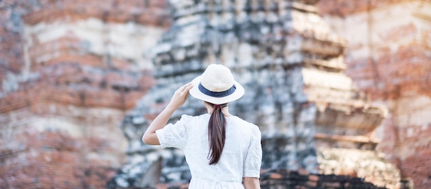 Donna turistica in abito bianco in visita all'antico stupa nel tempio Wat Chaiwatthanaram nel parco storico di Ayutthaya, estate, Asia e Thailandia concetto di viaggio