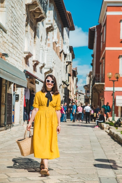 Donna turistica in prendisole giallo che cammina per una piccola strada cittadina croata
