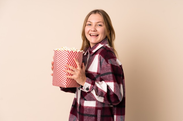 Donna ucraina dell'adolescente isolata su spazio beige che tiene un grande secchio di popcorn