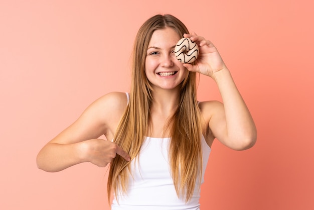 Donna ucraina dell'adolescente isolata su spazio rosa che tiene una ciambella e felice