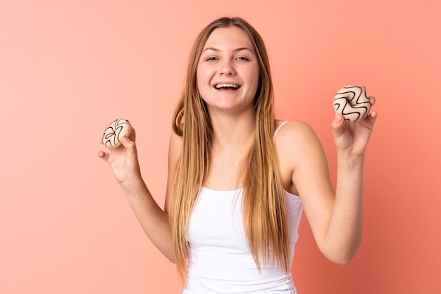 Donna ucraina dell'adolescente isolata sulle ciambelle rosa della tenuta dello spazio con l'espressione felice