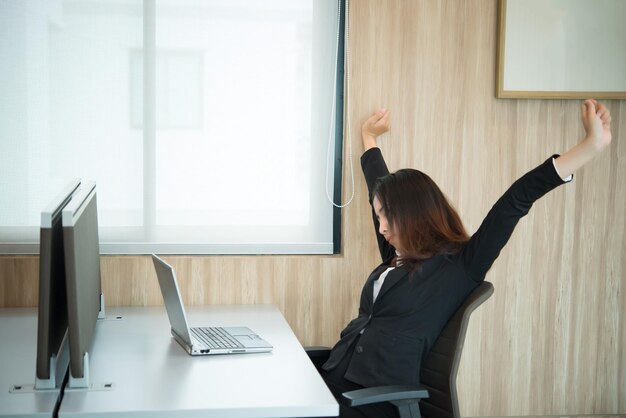 Donna ufficiale asiatica che allunga il corpo alla scrivania dell'ufficio dall'angolo posteriore Persone della Thailandia Donna d'affari stanca dal duro lavoro