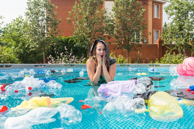 Donna urlante con un sacchetto di plastica sopra la testa in una piscina sporca.