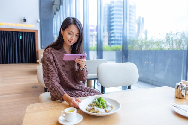 Donna usa il cellulare per scattare foto al suo pasto