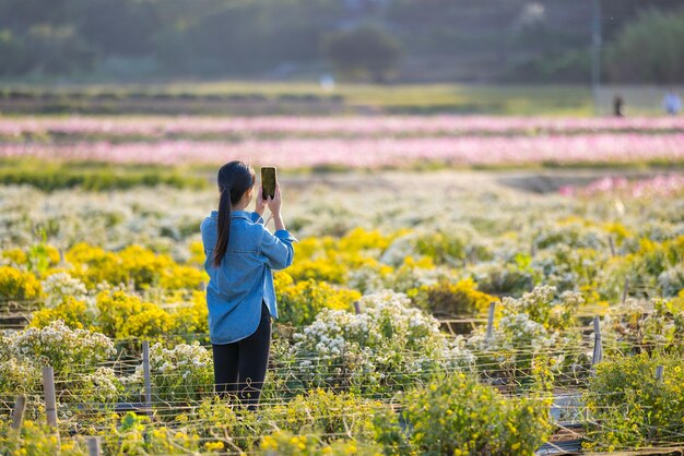 Donna usa il cellulare per scattare una foto in una fattoria di fiori