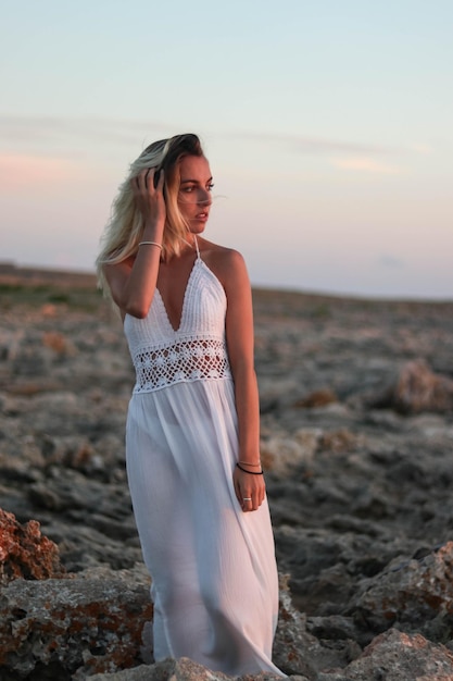 Donna vestita con abiti vintage sulle rocce del deserto al tramonto