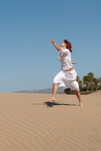 donna vestita di bianco che si gode le dune di sabbia in una soleggiata giornata primaverile o estiva