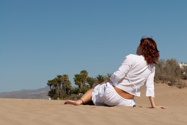 donna vestita di bianco che si gode le dune di sabbia in una soleggiata giornata primaverile o estiva