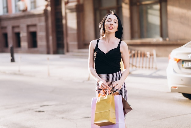 Donna vestita di moda con borse della spesa colorate per le strade, concetto di shopping