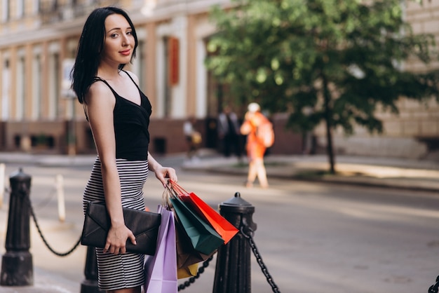 Donna vestita di moda con borse della spesa colorate per le strade, concetto di shopping