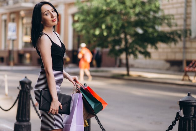 Donna vestita di moda con borse della spesa colorate per le strade, concetto di shopping