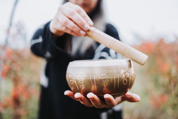 Donna vestita di nero che tiene e suona una campana tibetana con un bastone di legno