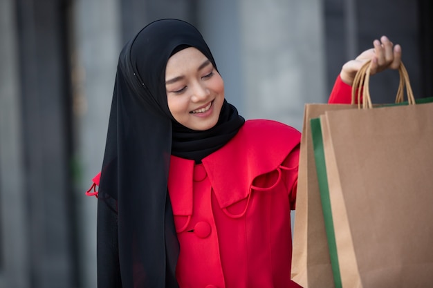 donna vestita di rosso con borse della spesa che cammina all'aperto