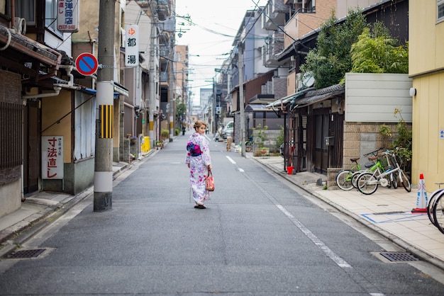 Donna vestita in costume tradizionale giapponese che cammina sotto i tori gate al santuario fushimiinari Kyoto Japan