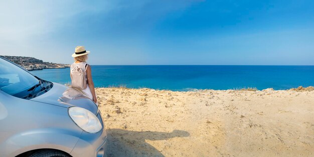 Donna viaggiatore in piedi in auto in spiaggia guardando il mare. Banner.