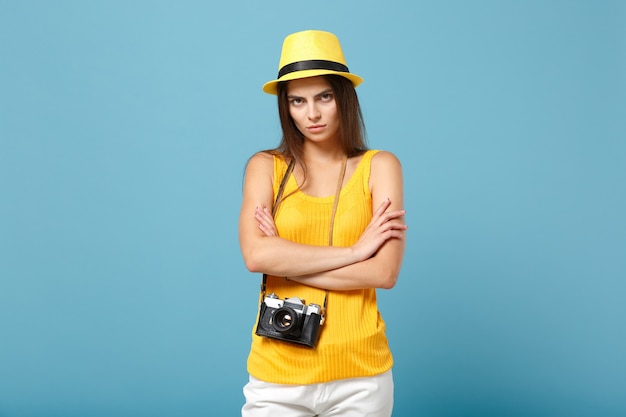 Donna viaggiatrice in abiti casual estivi gialli e cappello con macchina fotografica su blu