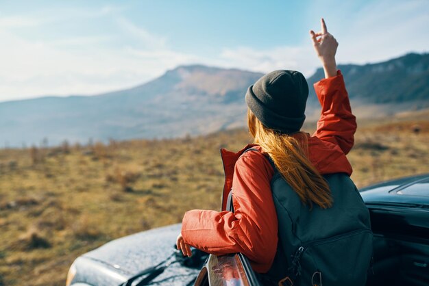 Donna vicino a automobili che gesturing con le sue mani sulla natura in montagna autunno turismo viaggio zaino