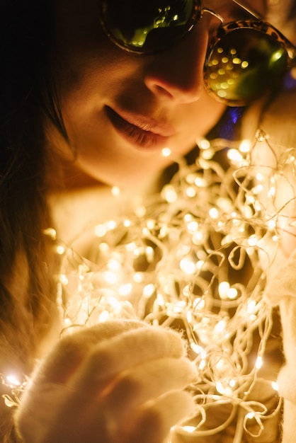 Donna vicino a un albero di Natale sulla strada con ghirlande nelle sue mani