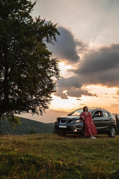 Donna vicino all'auto Tramonto in montagna