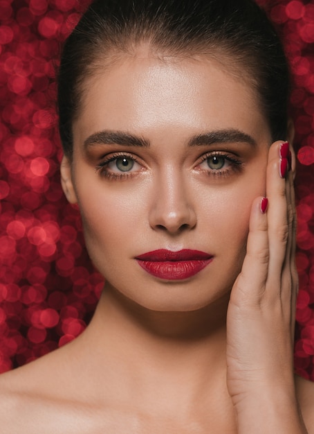 Donna viso partito bellezza rossetto rosso pelle pulita bello fascino femminile. Sfondo di paillettes rosse