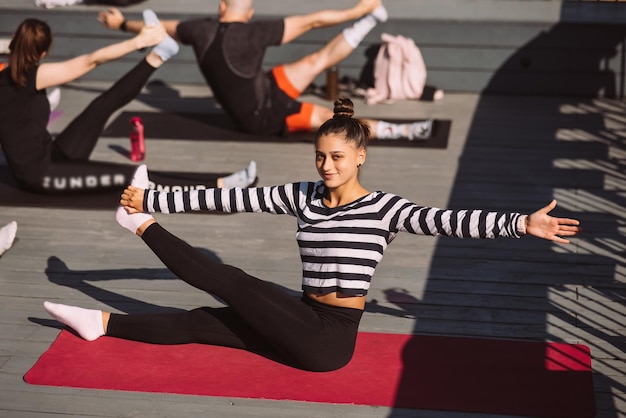 Donna Yogi e gruppo eterogeneo di sportivi che praticano yoga