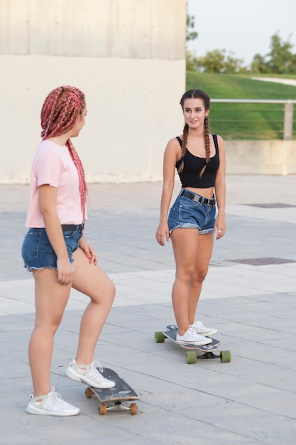 Donne adolescenti divertirsi e pattinare con tavole lunghe