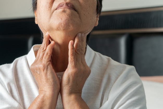 Donne adulte senior che toccano il collo sensazione di malessere tosse con mal di gola.