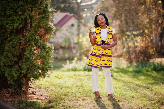 Donne afroamericane alla moda in giacca gialla poste in strada con bevanda calda in tazza di carta usa e getta