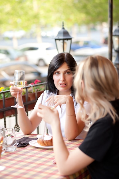 Donne al caffè che bevono vino bianco e parlano. Comunicazione e concetto di amicizia.