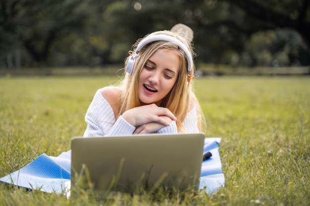 Donne americane che si siedono con le felicità sorridenti e ascoltano la musica nel parco per rilassarsi